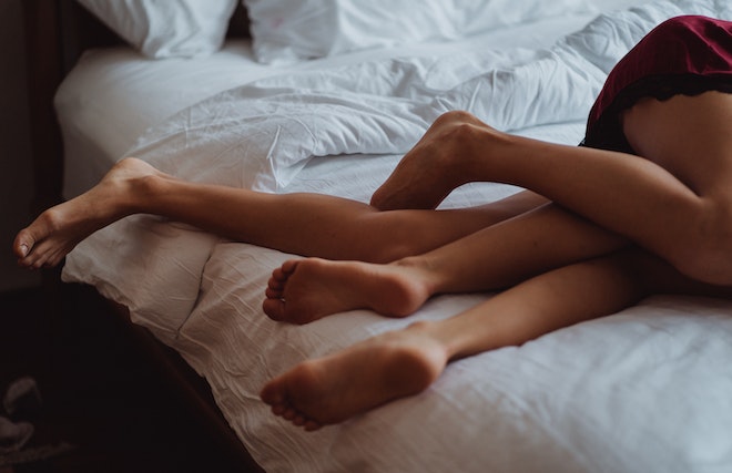 ベッドで絡み合う2人の足