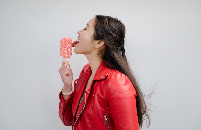 アイスキャンディーを舐める赤いライダースジャケットの女性