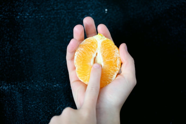 オレンジと女性の指