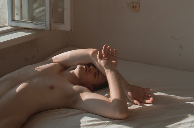 ベッドに裸で仰向けになる男性