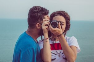 カメラを持つ女性に、キスをする男性