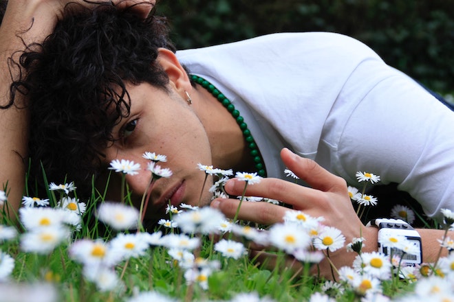 花の咲いているところに寝そべる男性