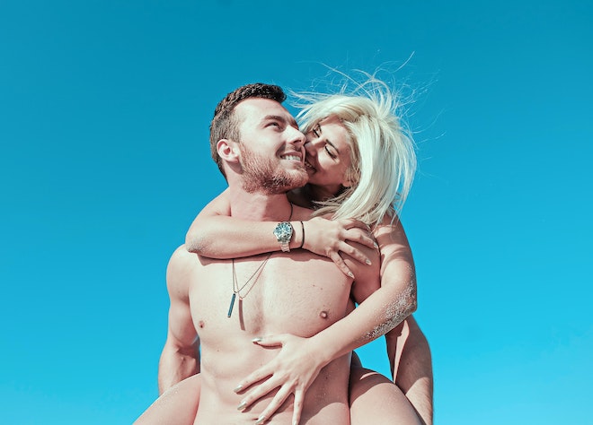 青い空を背景に、裸の男性の背に抱きつく女性